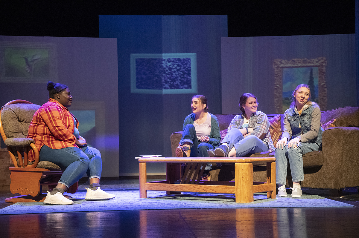 four women seated on theatre stage